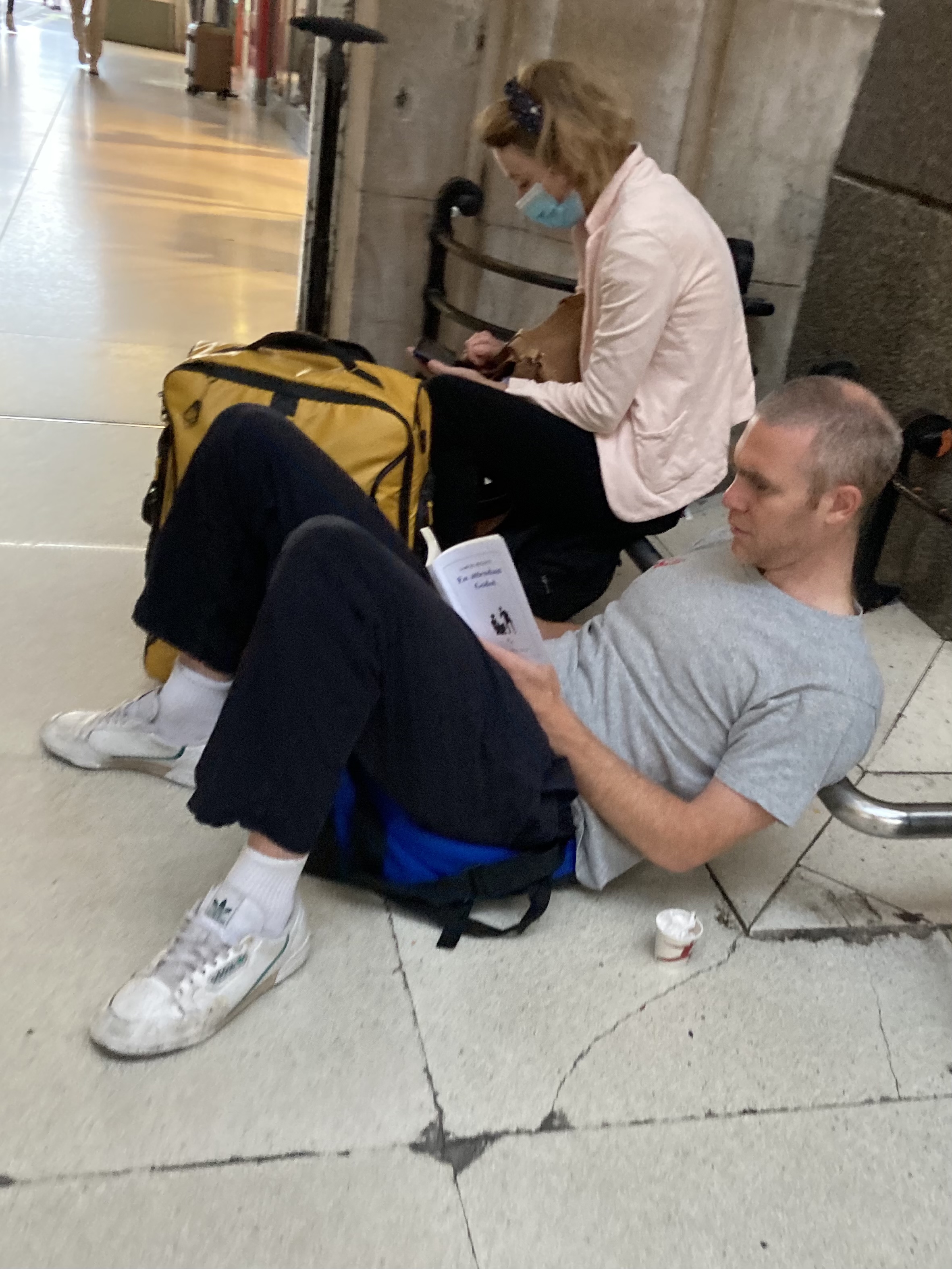 homme allongé gare deLyon en train de lire 